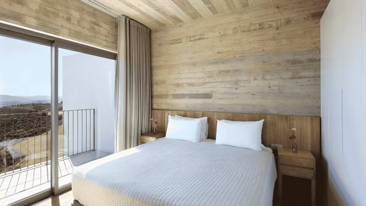 A comfy king size bed with the scenery of the Paphos mountains visible in the background at Minthis Resort.