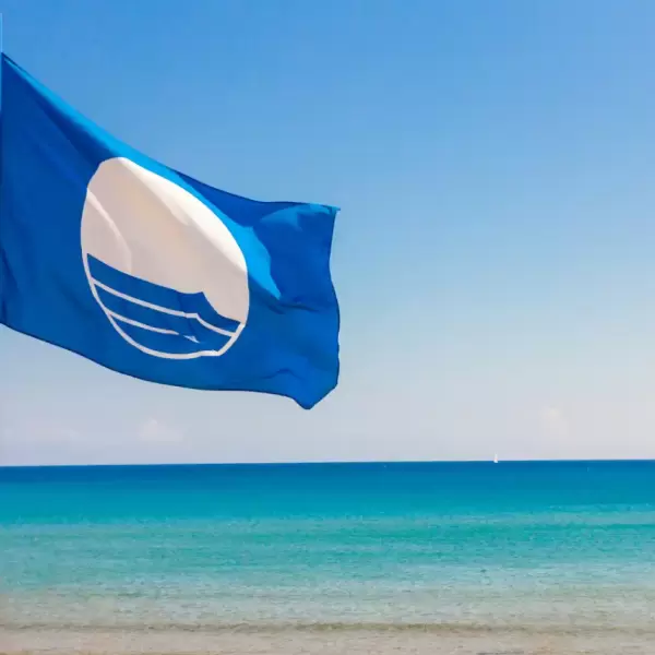 A blue flag at the beach which emphasizes the cleanliness of the sea waters