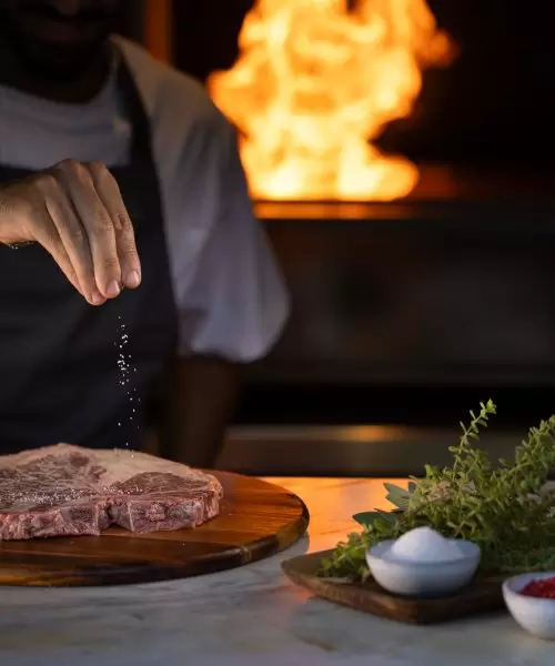 A chef drizzles salt onto a large piece of steak at Amaracus Restaurant in Paphos, Cyprus