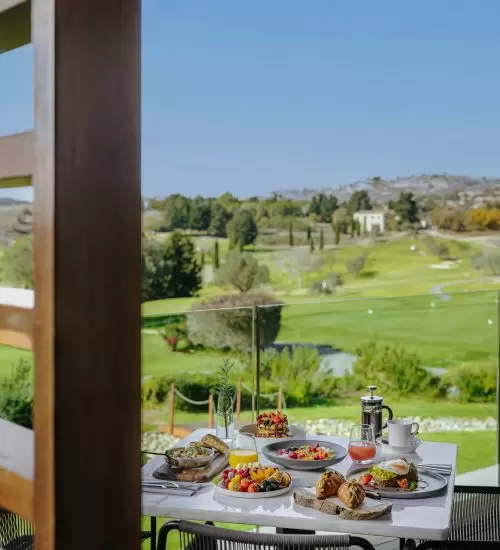 An outdoor table set at the Clubhouse restaurant with the Minthis Golf Course visible in the background