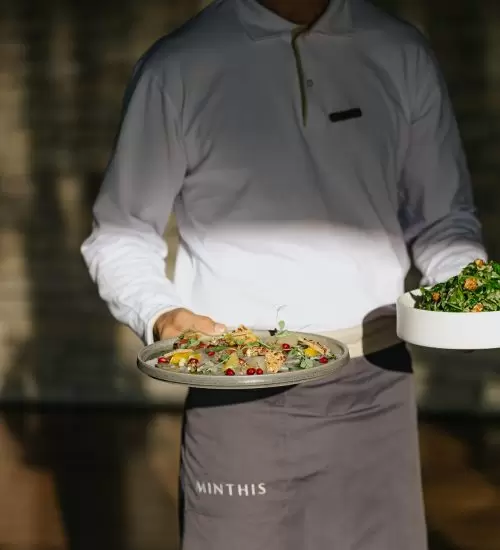 A Minthis waiter carries two dishes to a table at Amaracus Restaurant in Paphos, Cyprus