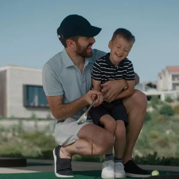 A golfing Dad embraces his son while golfing at Minthis Resort
