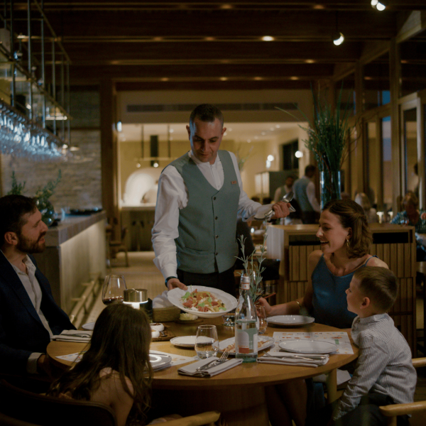 A family dining at the Minthis Restaurant are shown a dish by the waiter