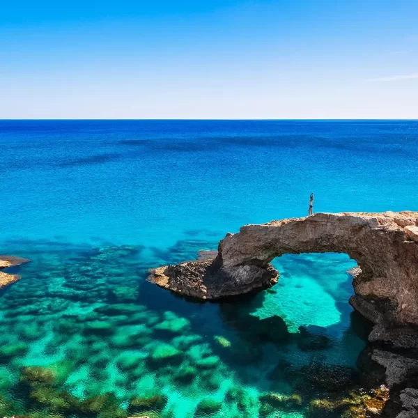 The beautiful blue waters at Protaras with a tourist stretching on the rocks center of image