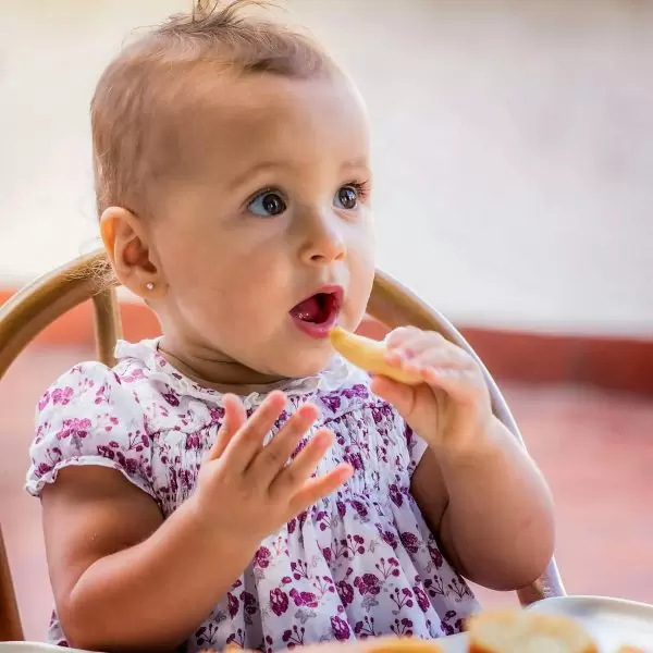 A toddler eating a snack while being entertained at Minthis Resort
