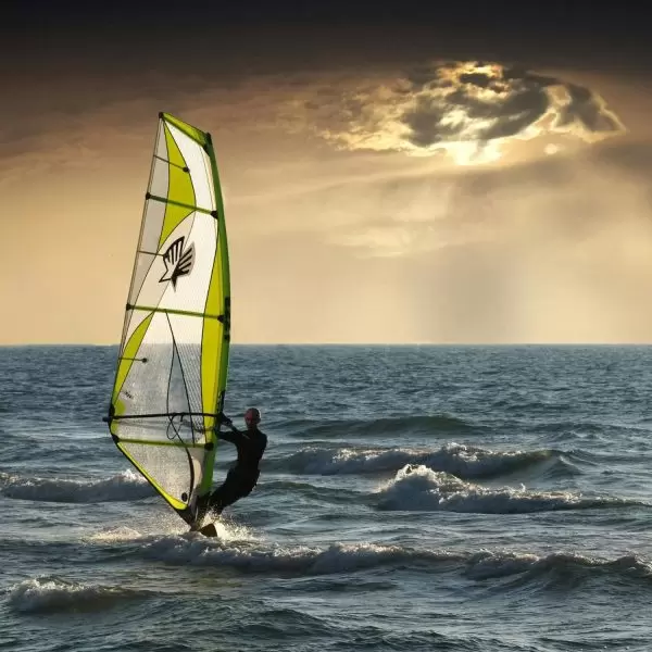 A windsurfer makes their way across the Mediterranean Sea at sunset in Paphos